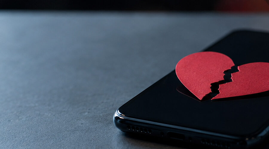 Breaking up with a text message represented by a smartphone beside a separated heart in a quiet evening setting